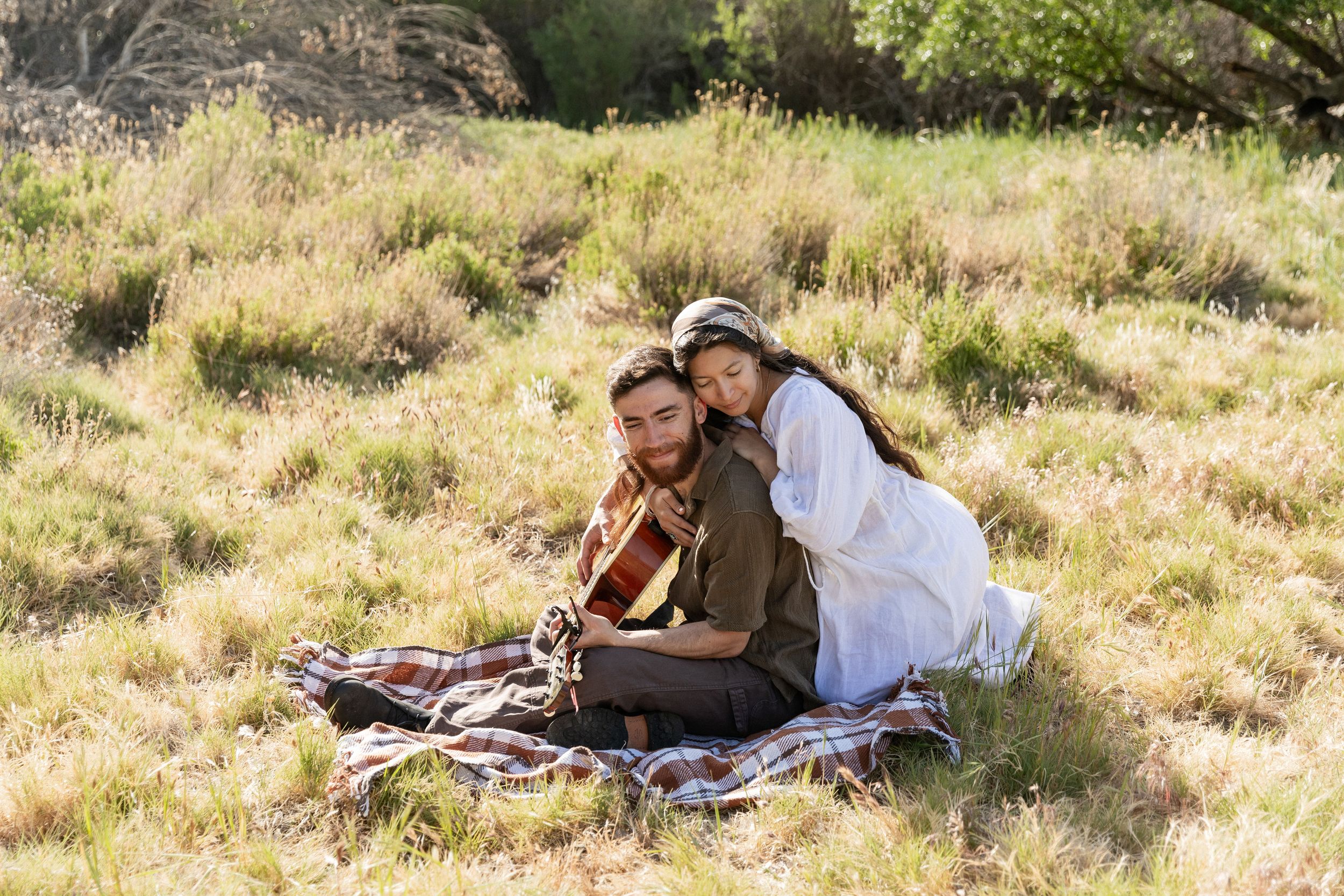 Couple having romantic picnic with guitar on sunny hillside meadow, eastern nc photographer
