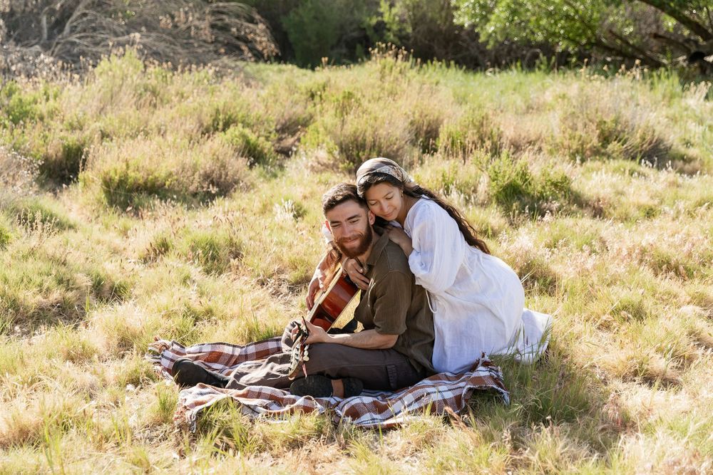 Couple having romantic picnic with guitar on sunny hillside meadow, eastern nc photographer