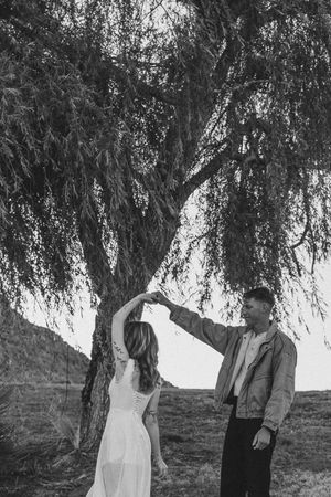 Black and white photo of couple dancing romantically under a willow tree in an outdoor rural setting in North Carolina.