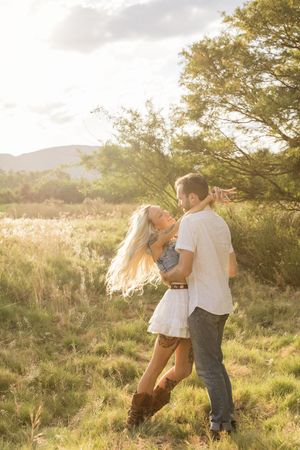 Couple dancing together in a sunlit meadow with trees and mountains in the background in NC.