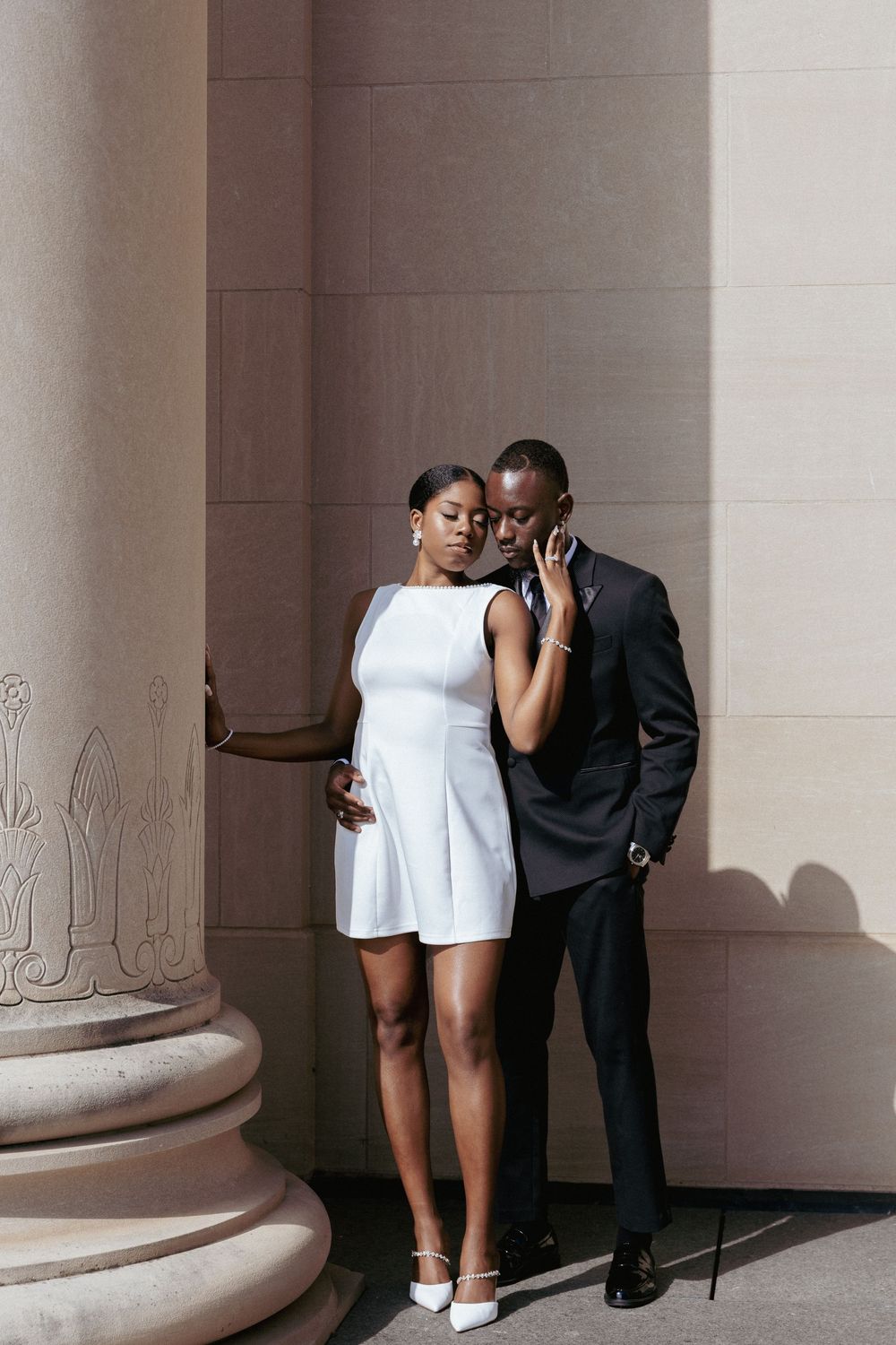 A couple shares an intimate moment in a series of four architectural frames with stone columns.