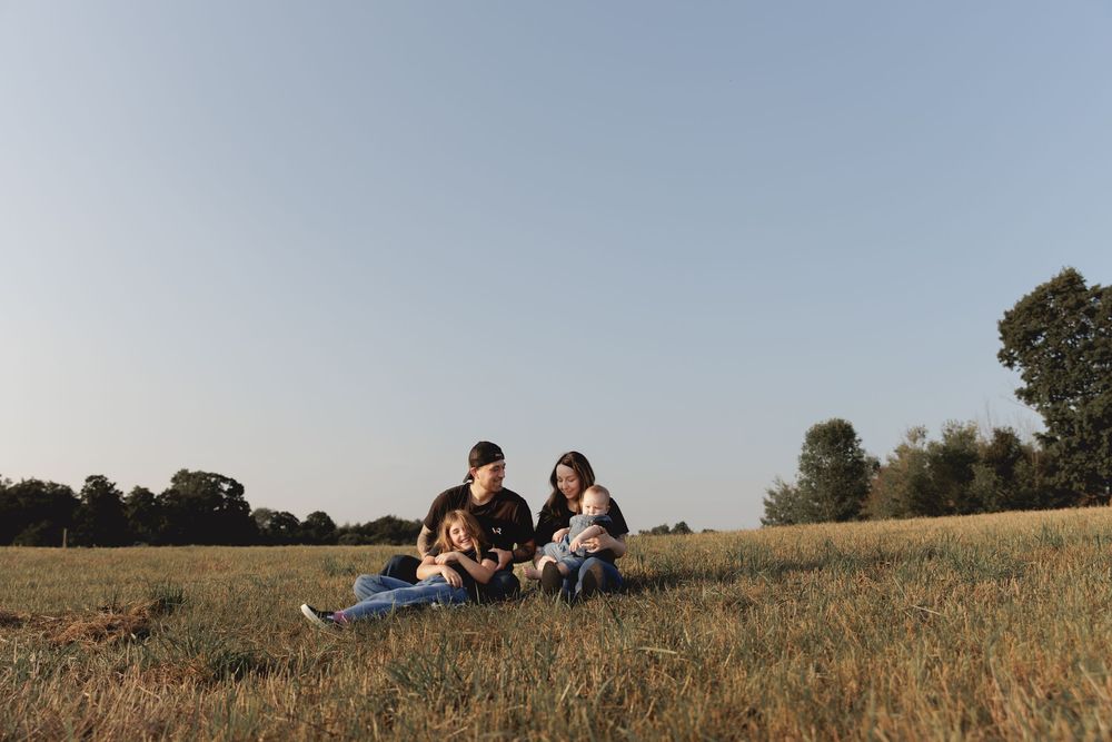 People relaxing together in a sunny field with tall grass and blue sky on a summer afternoon.