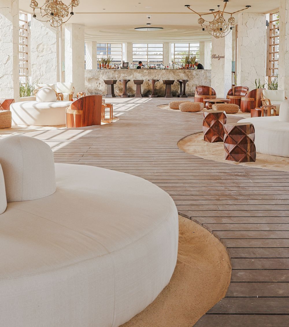 Modern minimalist interior with curved white walls, wooden floors and natural light streaming through windows.