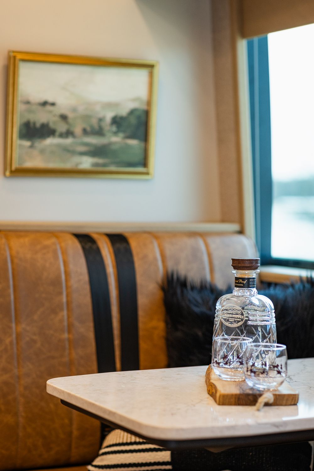 Restaurant interior with brown leather booth seating, white tables and framed artwork on blue walls.