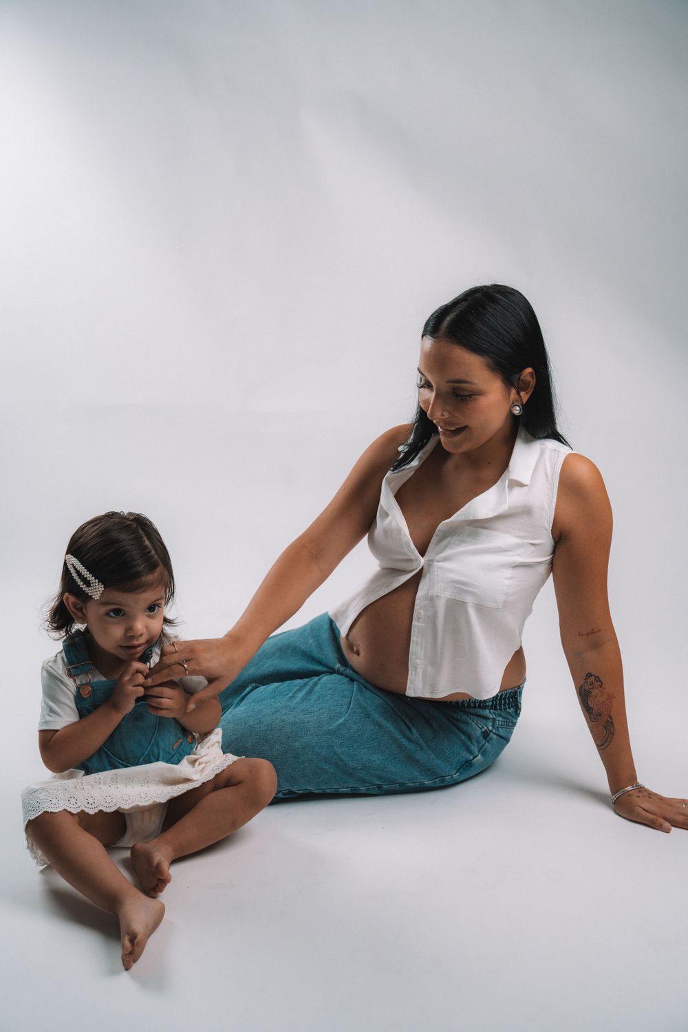 A mother and child share laughter during a casual studio photoshoot.