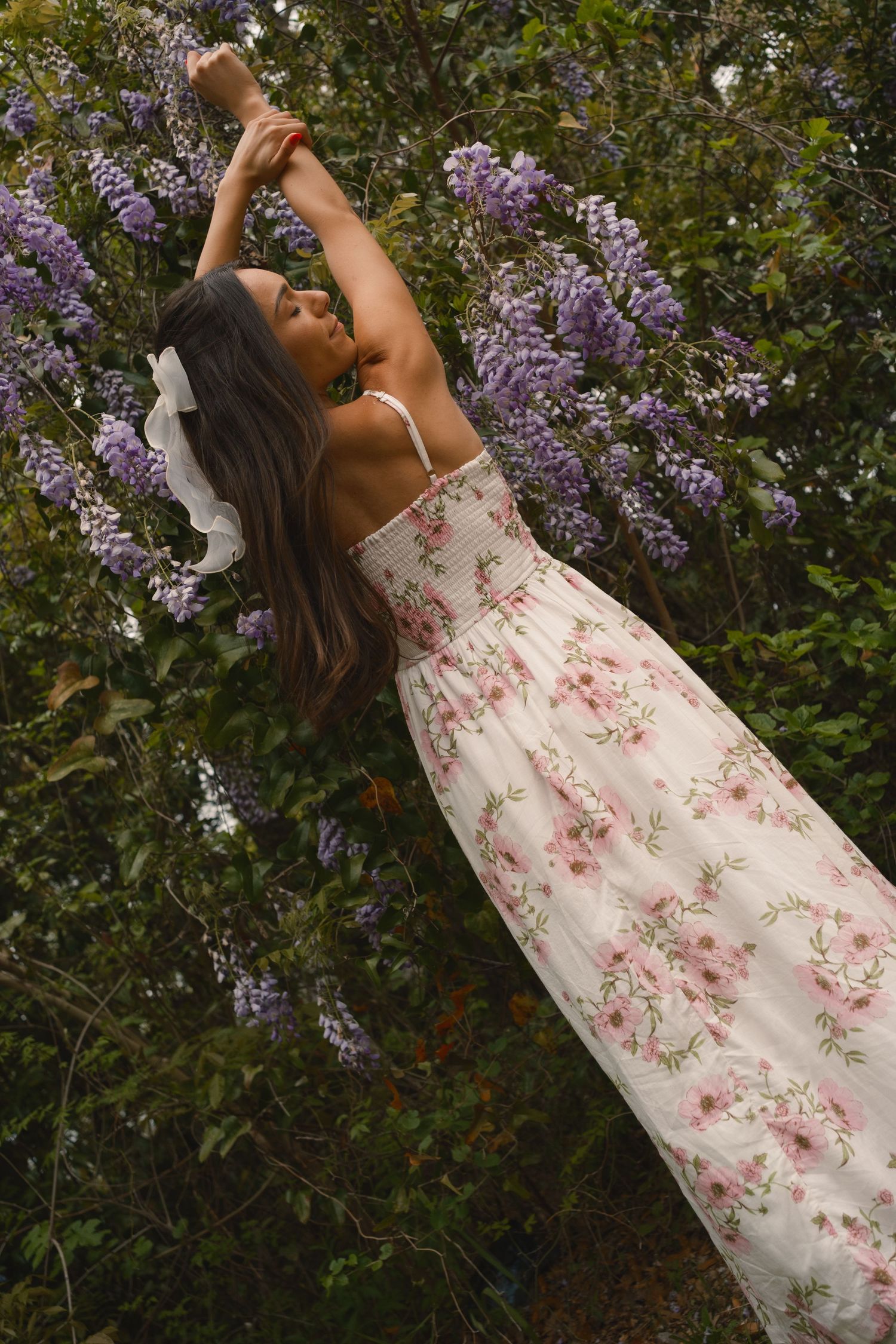 Hampton Park portrait session of a woman standing by a blooming wisteria tree in Charleston South Carolina