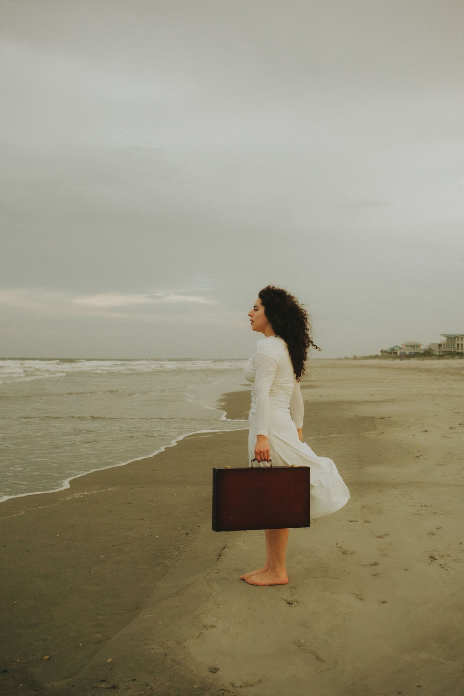 Woman standing at the shoreline gazing at the waves on Folly Beach in Charleston SC