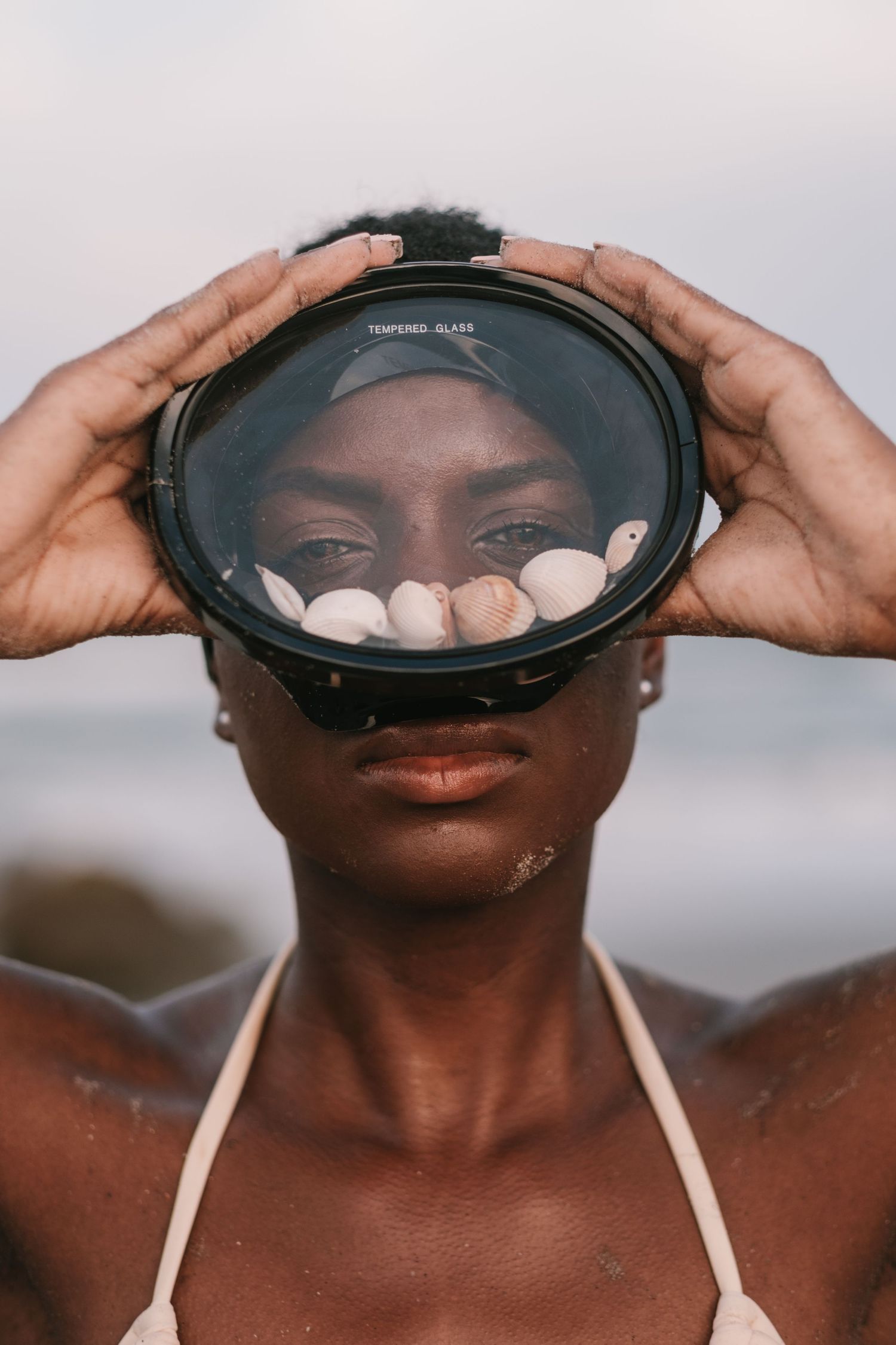 Sunset portrait session of a woman in a bikini posing with seashells on the beach