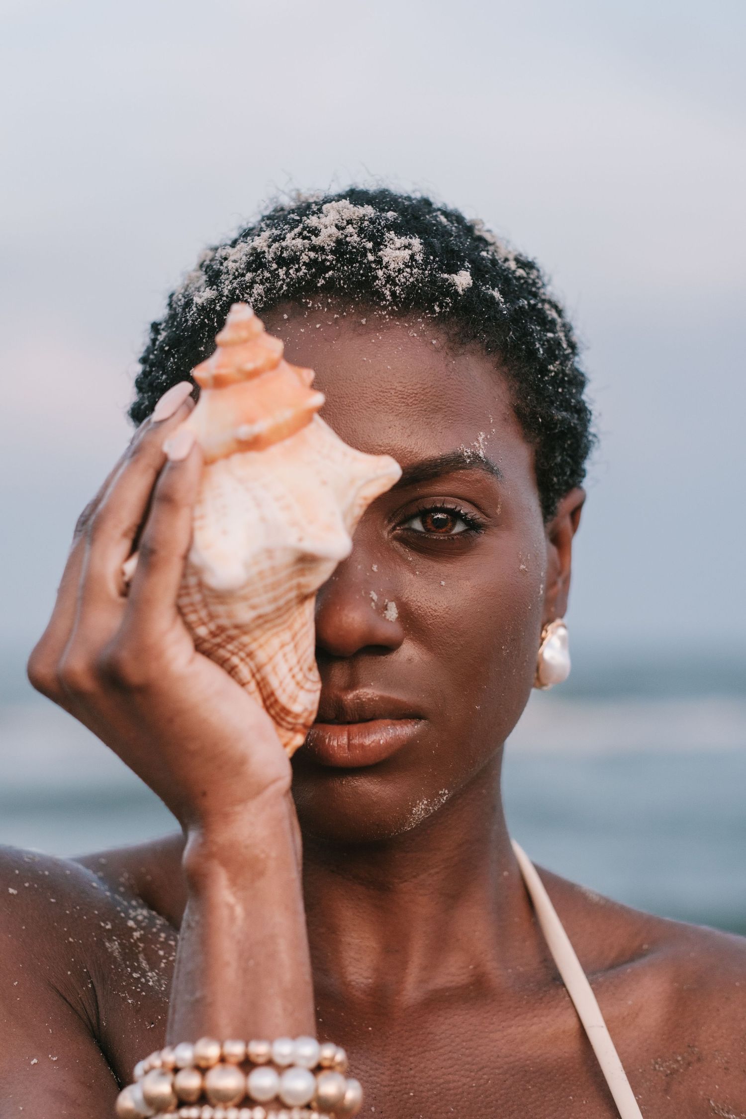 Folly Beach sunset photoshoot featuring a woman in a bikini holding seashells by the shoreline