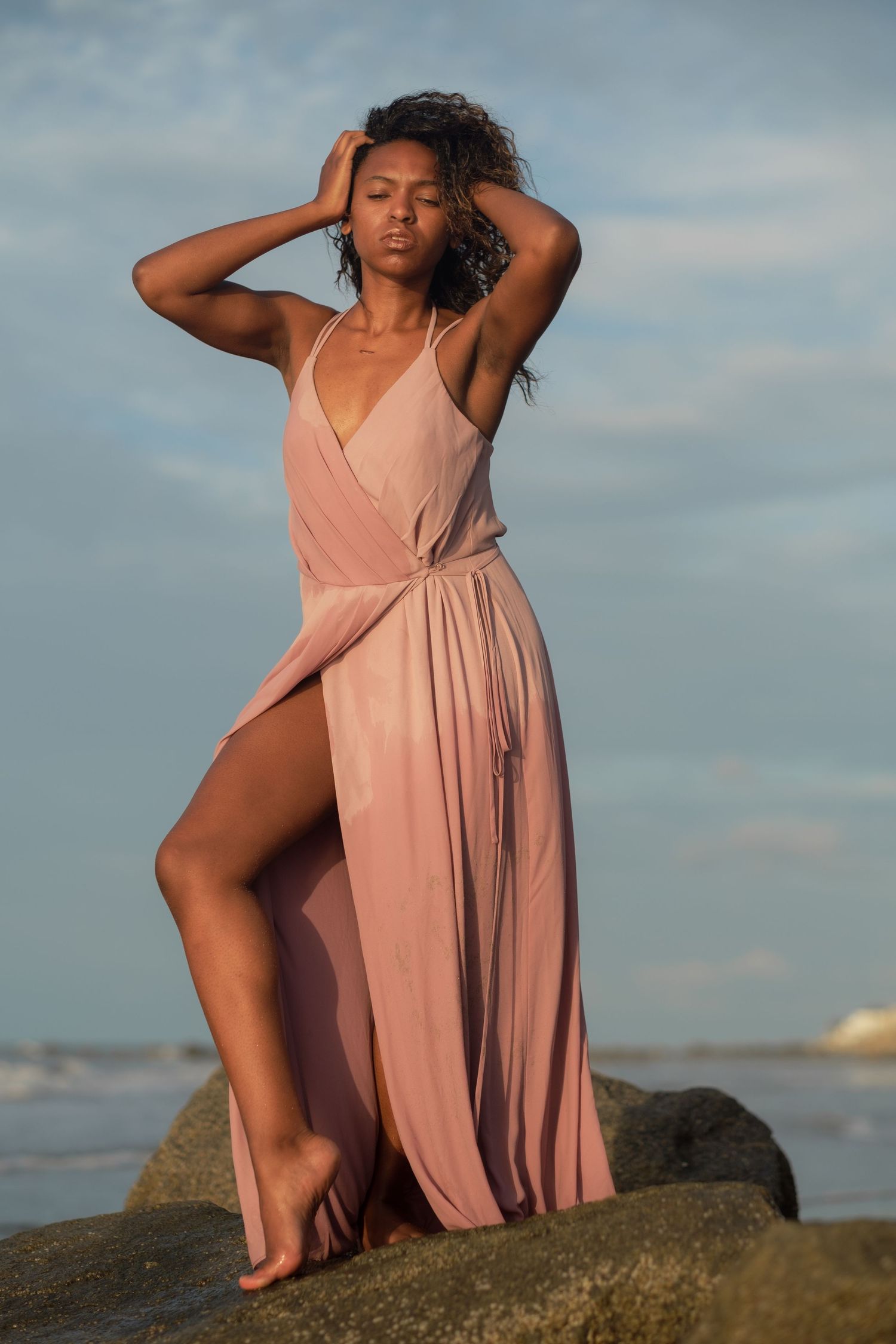 Folly Beach portrait of a woman standing on coastal rocks wearing a long flowing gown