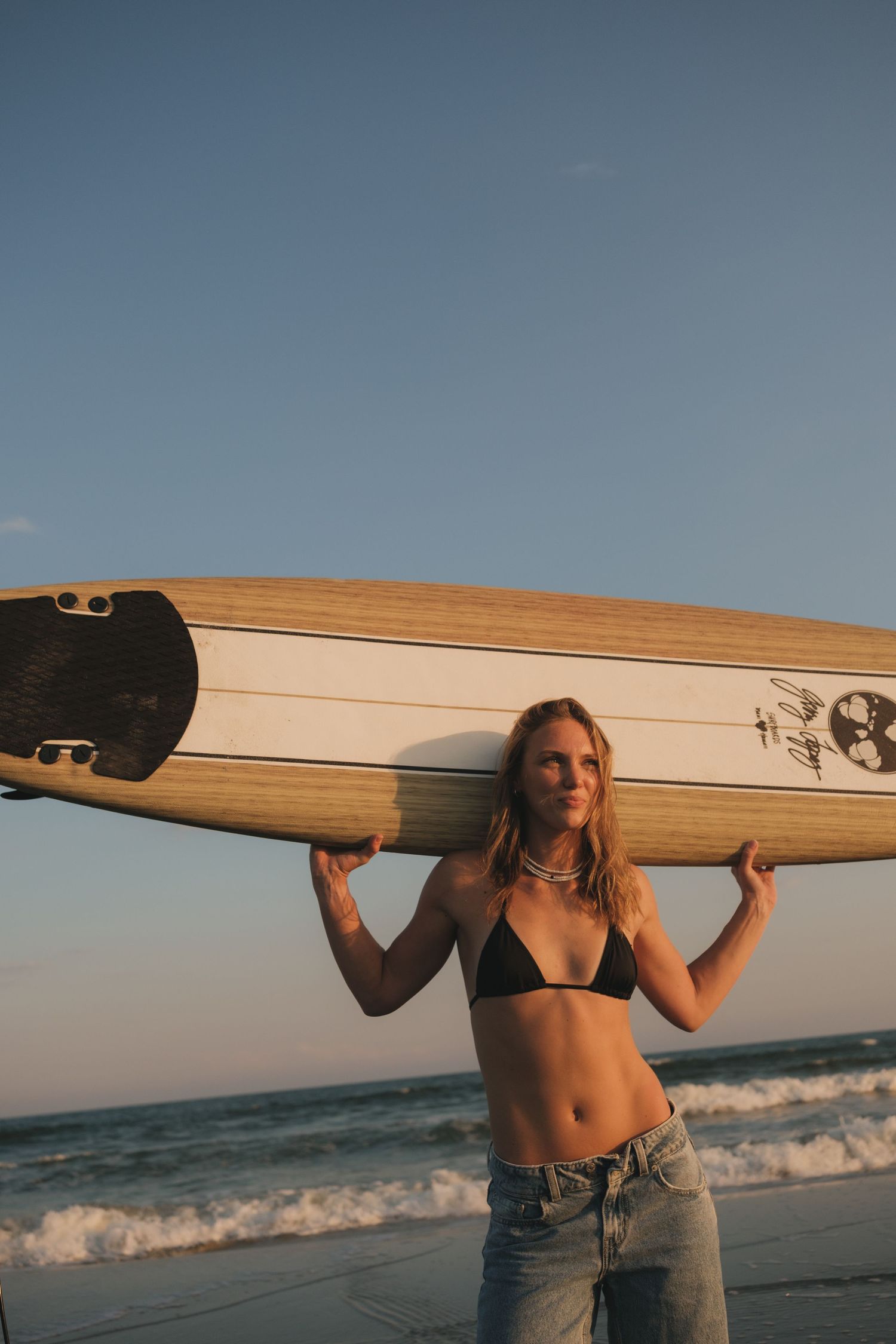 Young female surfer holding her board during a portrait session on Folly Beach, Charleston