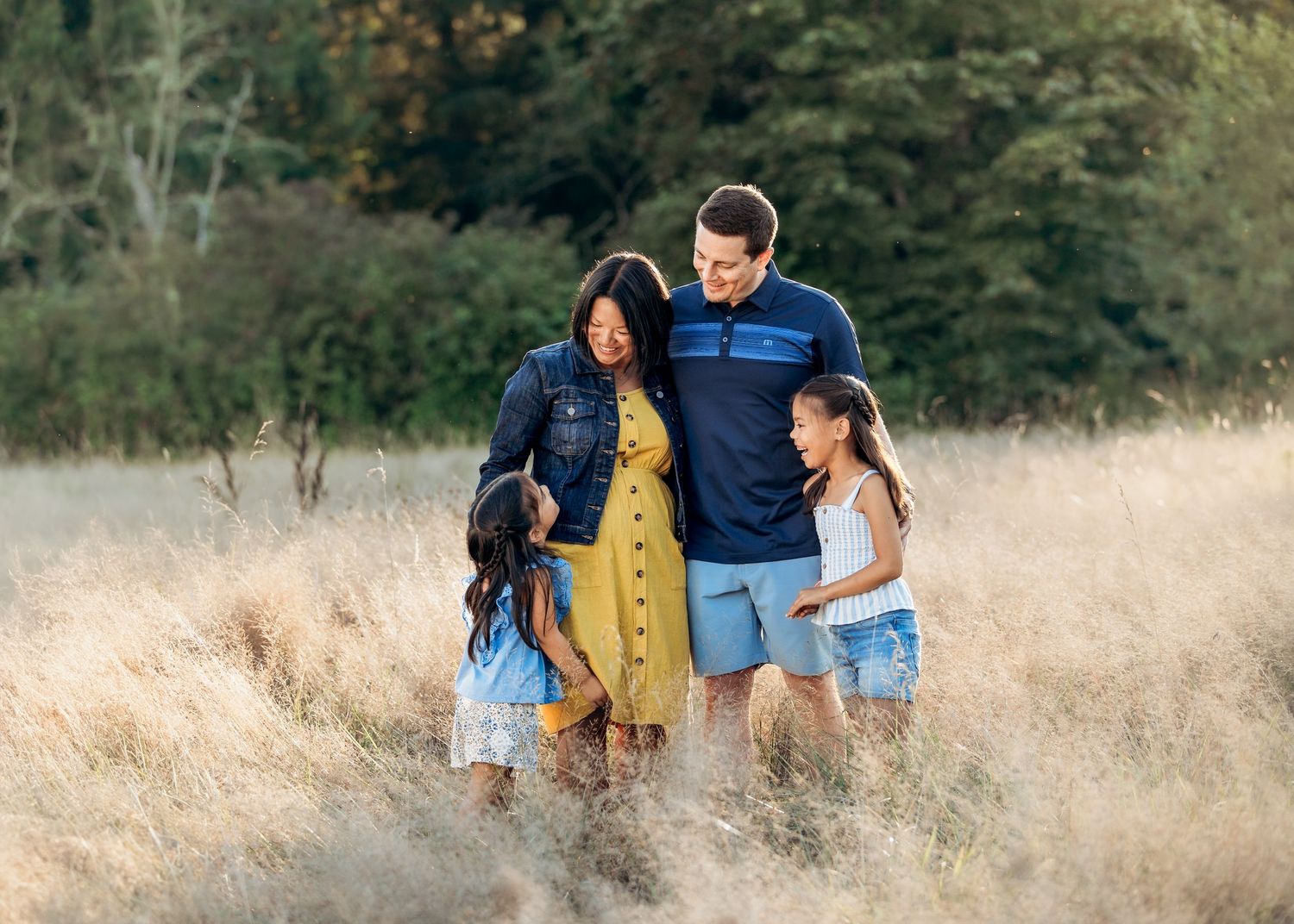 Family walking through tall golden grass field during outdoor photo session.