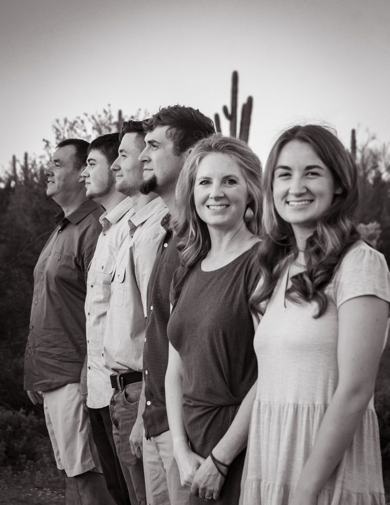 Group poses together outdoors in casual attire for black and white portrait.