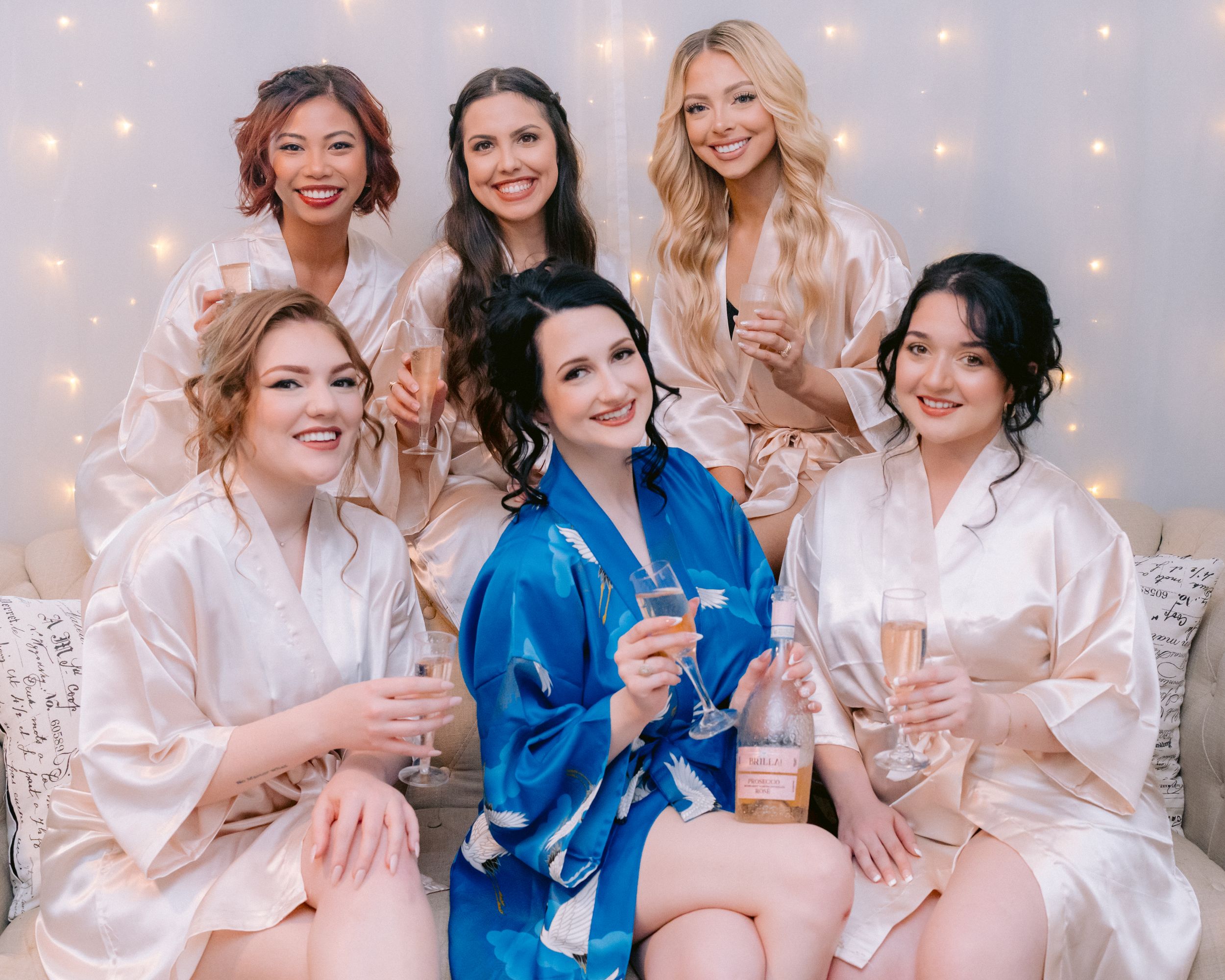Celebratory group photo with one person in blue robe and others in pink robes against sparkling backdrop.