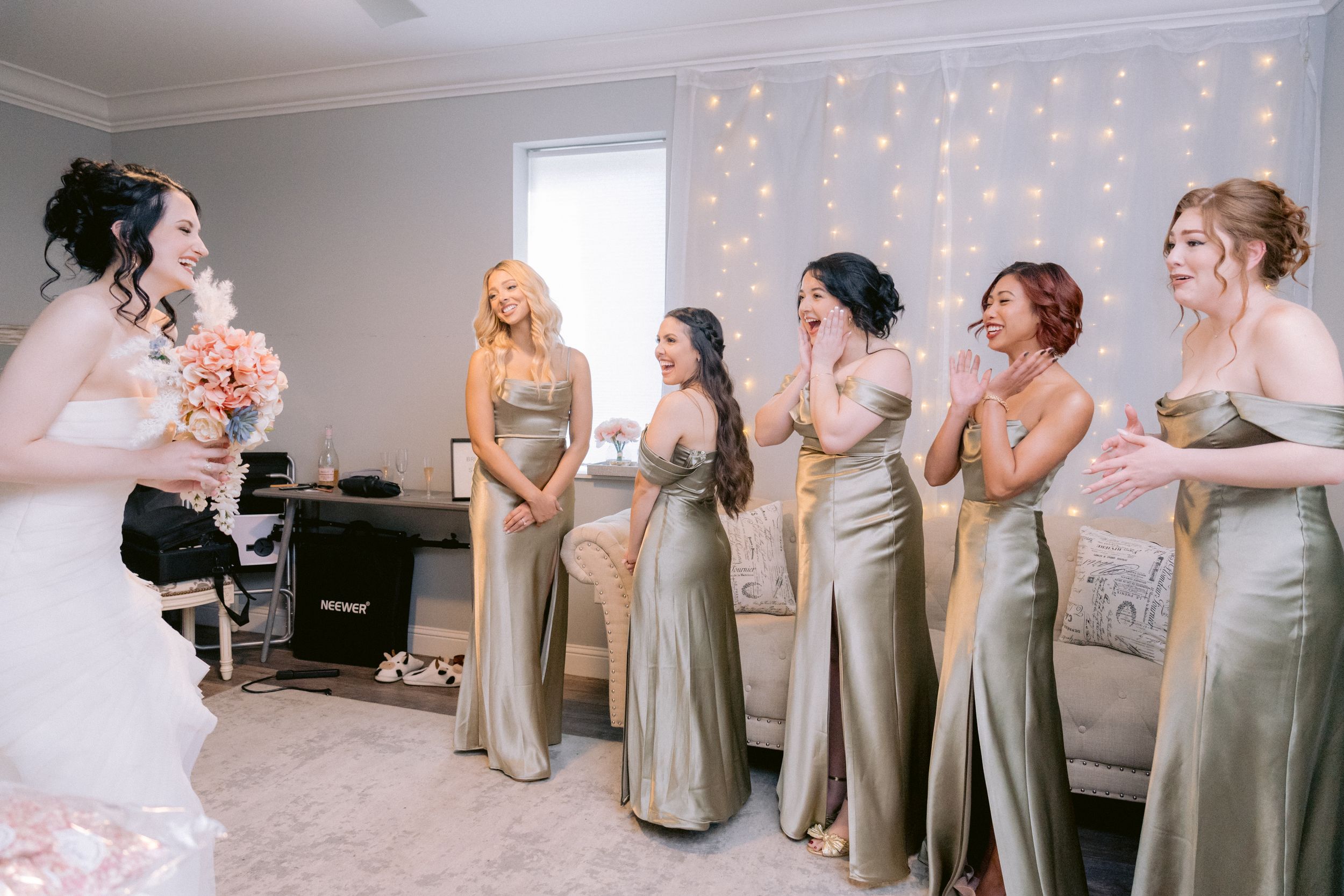 Bridesmaids in champagne dresses react emotionally during a wedding preparation moment.