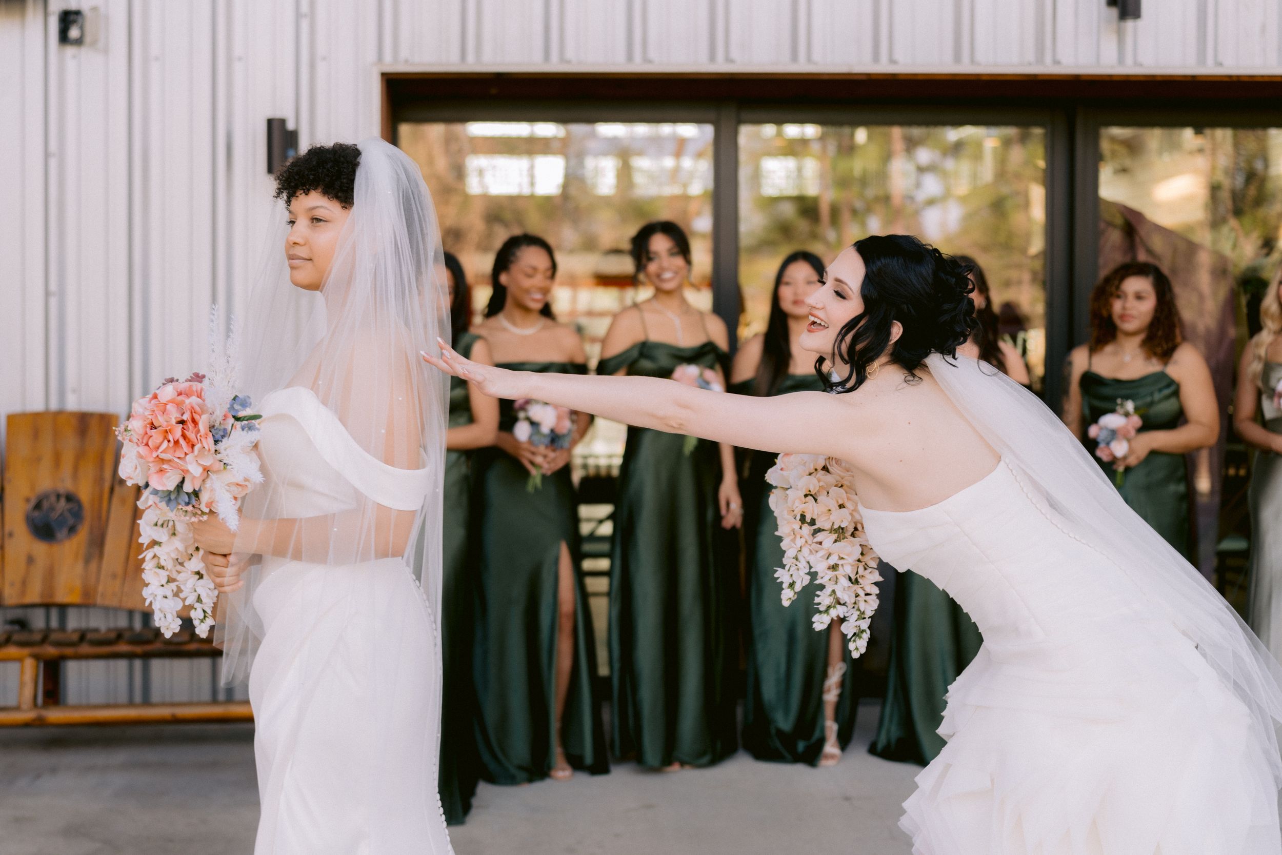 Two people in wedding attire perform a dance move in front of wedding party wearing green dresses.