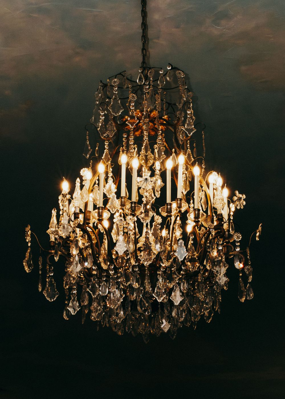 Elegant crystal chandelier photographed in sequence showing progressive lighting from dark to illuminated against moody background.
