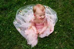Little girl sitting in grass in floral dress