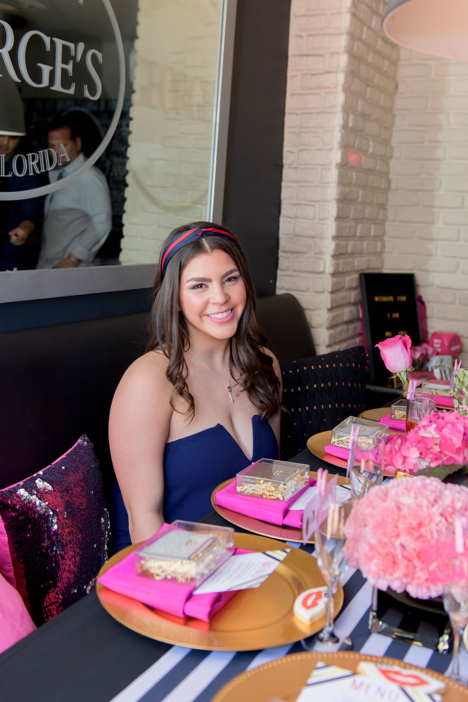 Table setting with pink florals and decorative place settings at a celebration.