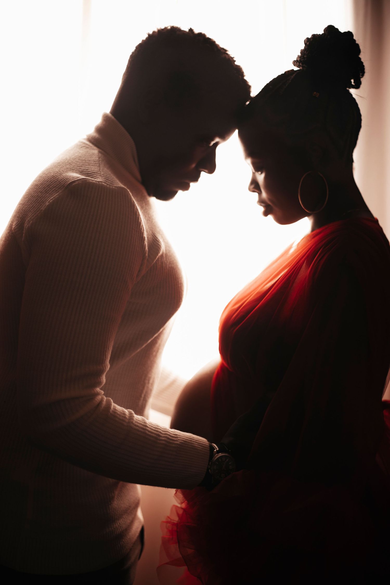 Silhouetted maternity photography session with dramatic backlighting.
