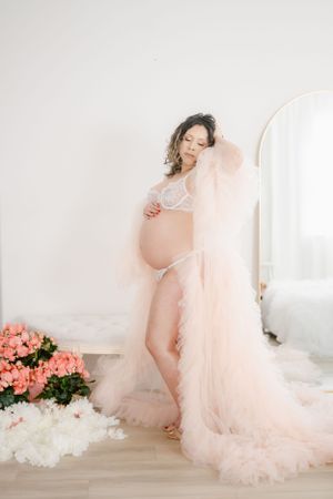 Romantic maternity portrait with flowing peach tulle gown and mirror reflection.