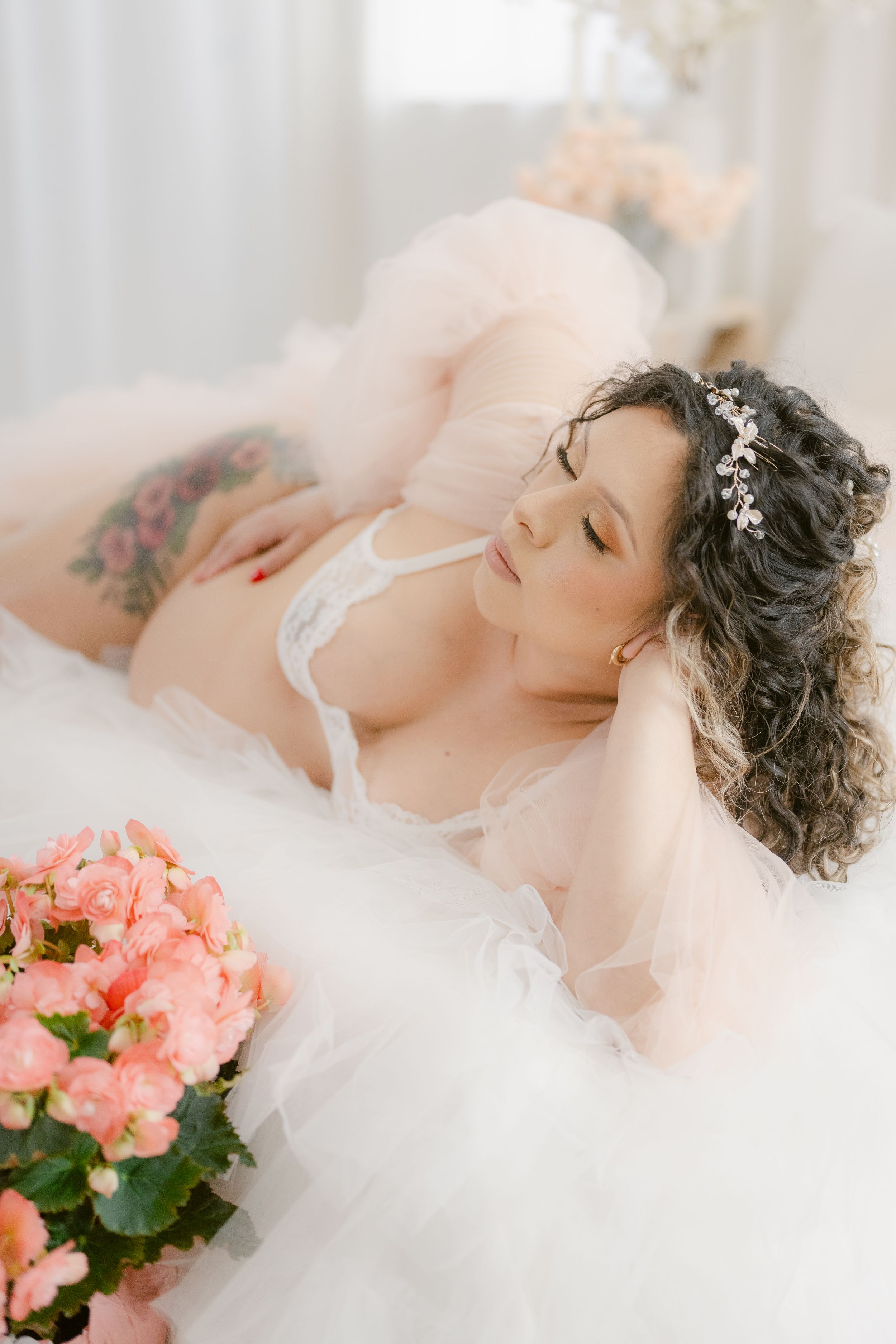 Romantic maternity boudoir photo with coral flowers and crystal hair accessories.