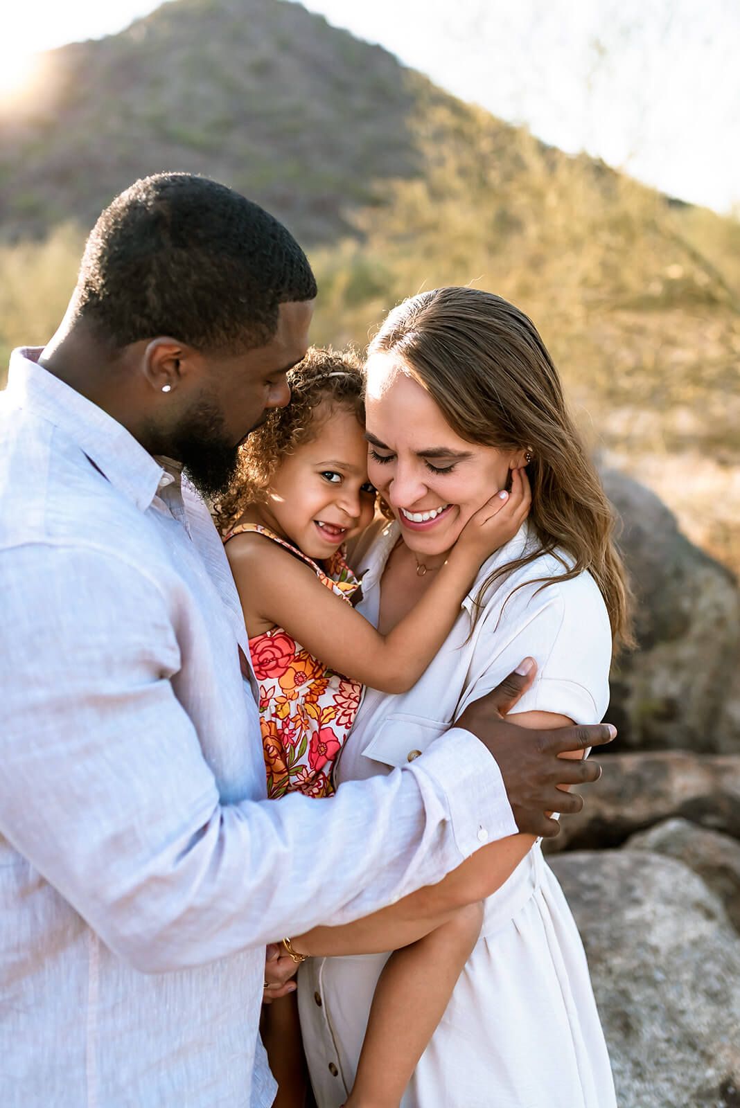 A loving family shares a tender moment together while outdoors against a mountainous backdrop at sunset in Scottdale.