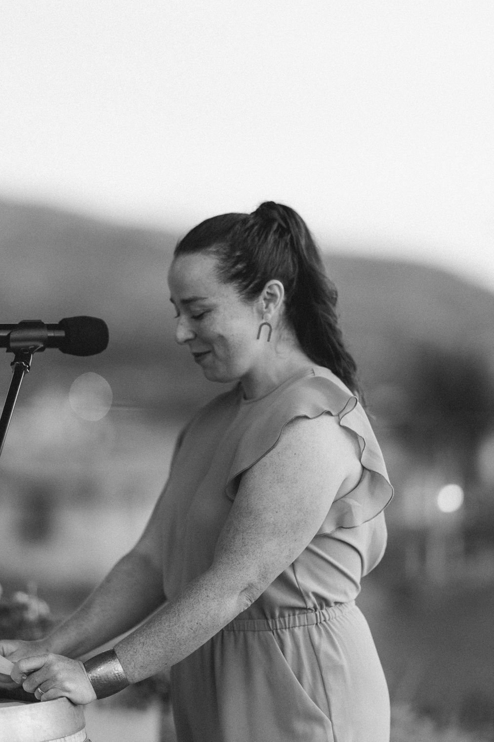 Speaker at podium during outdoor event in black and white photograph.