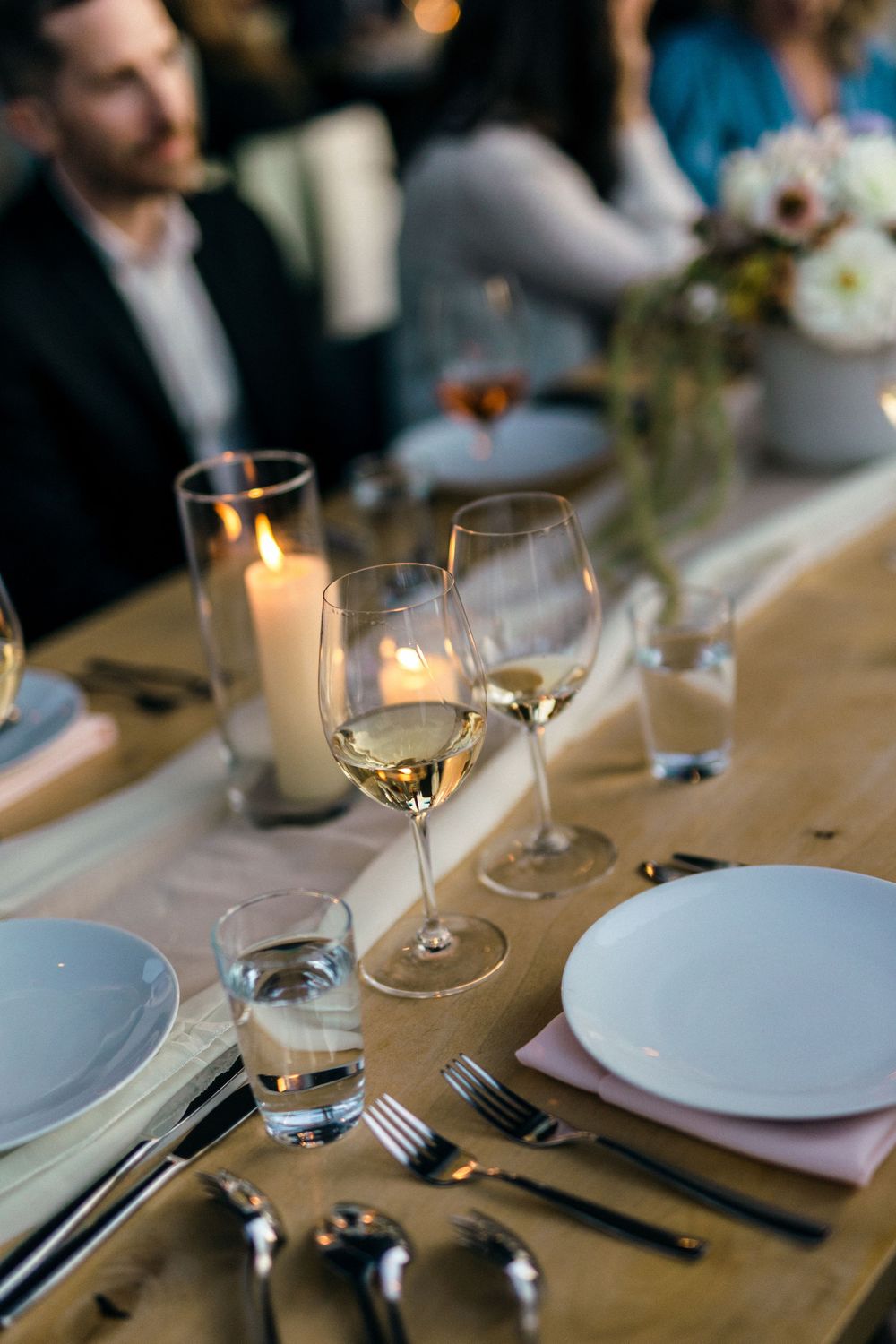 An elegant table setting with wine glasses, candles and place settings for a wedding reception.