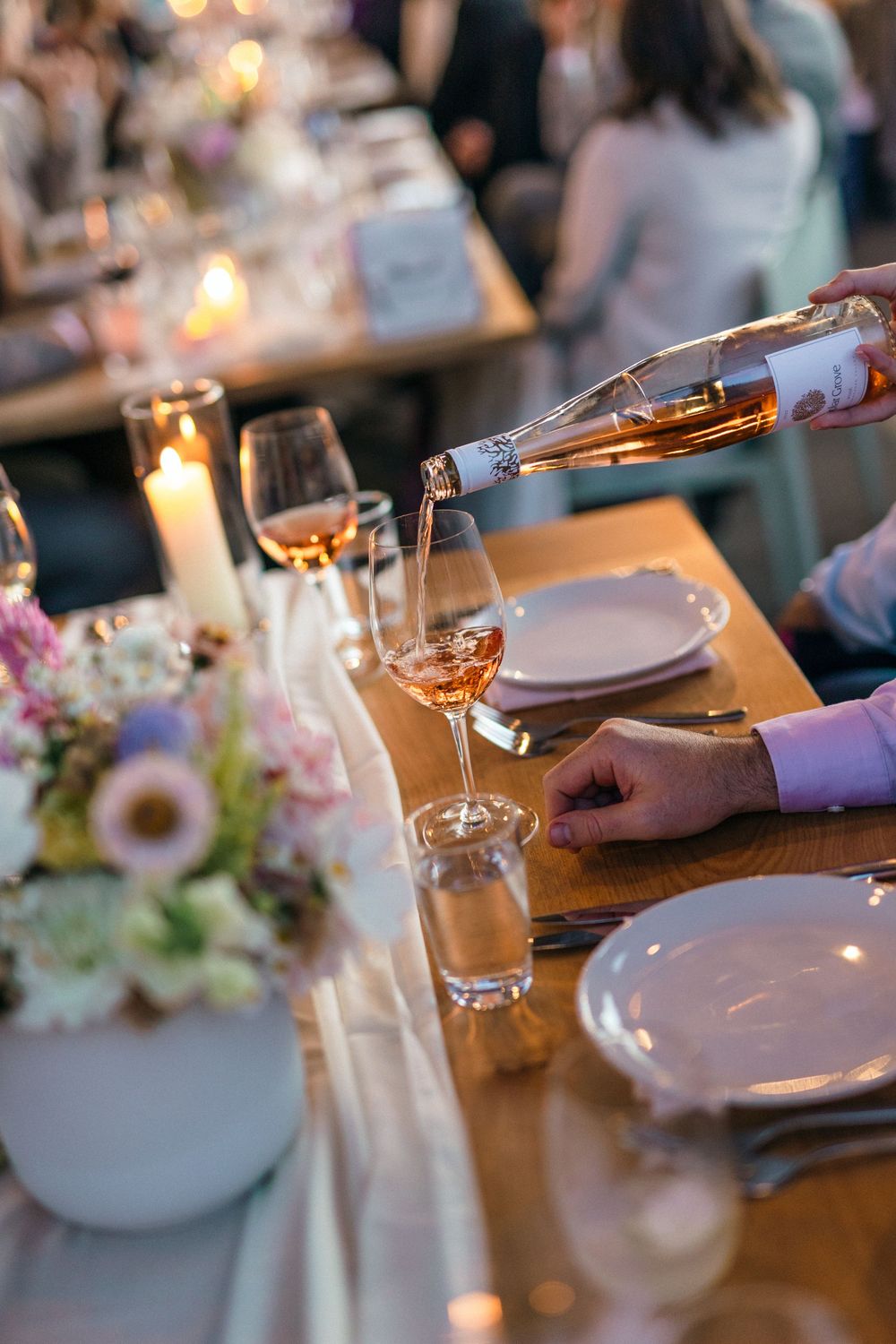 Rose wine being poured into glasses at an elegant wedding reception dinner table.