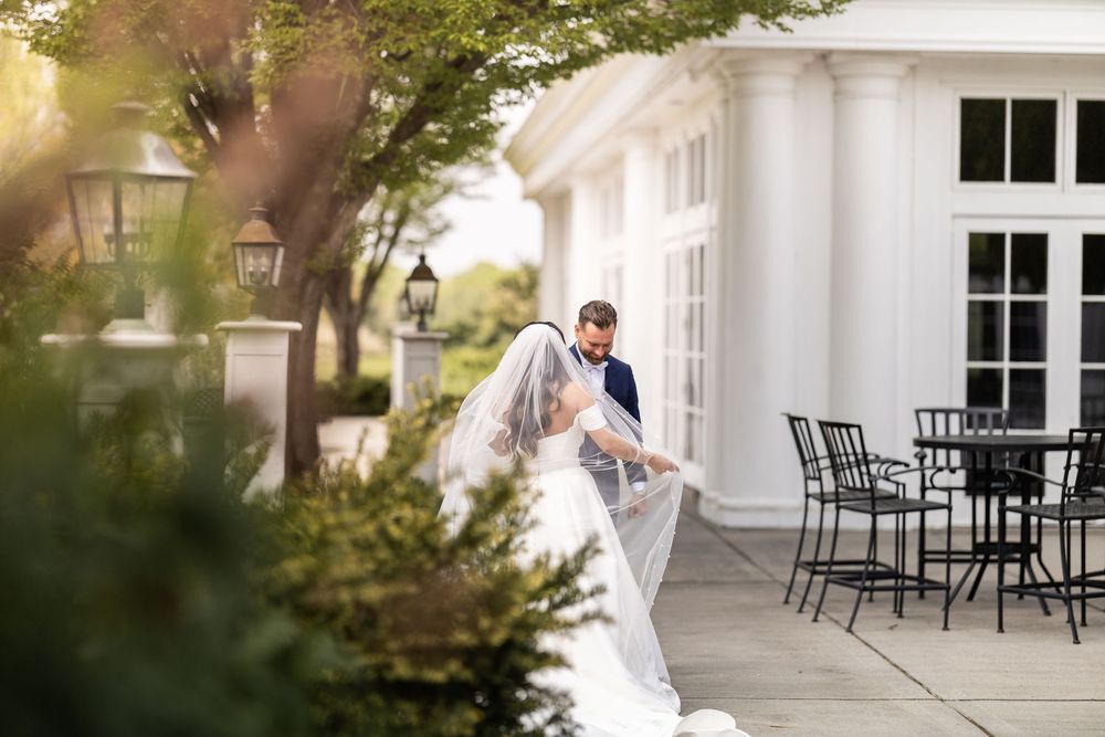 White colonial style house exterior with black outdoor furniture on wraparound porch.