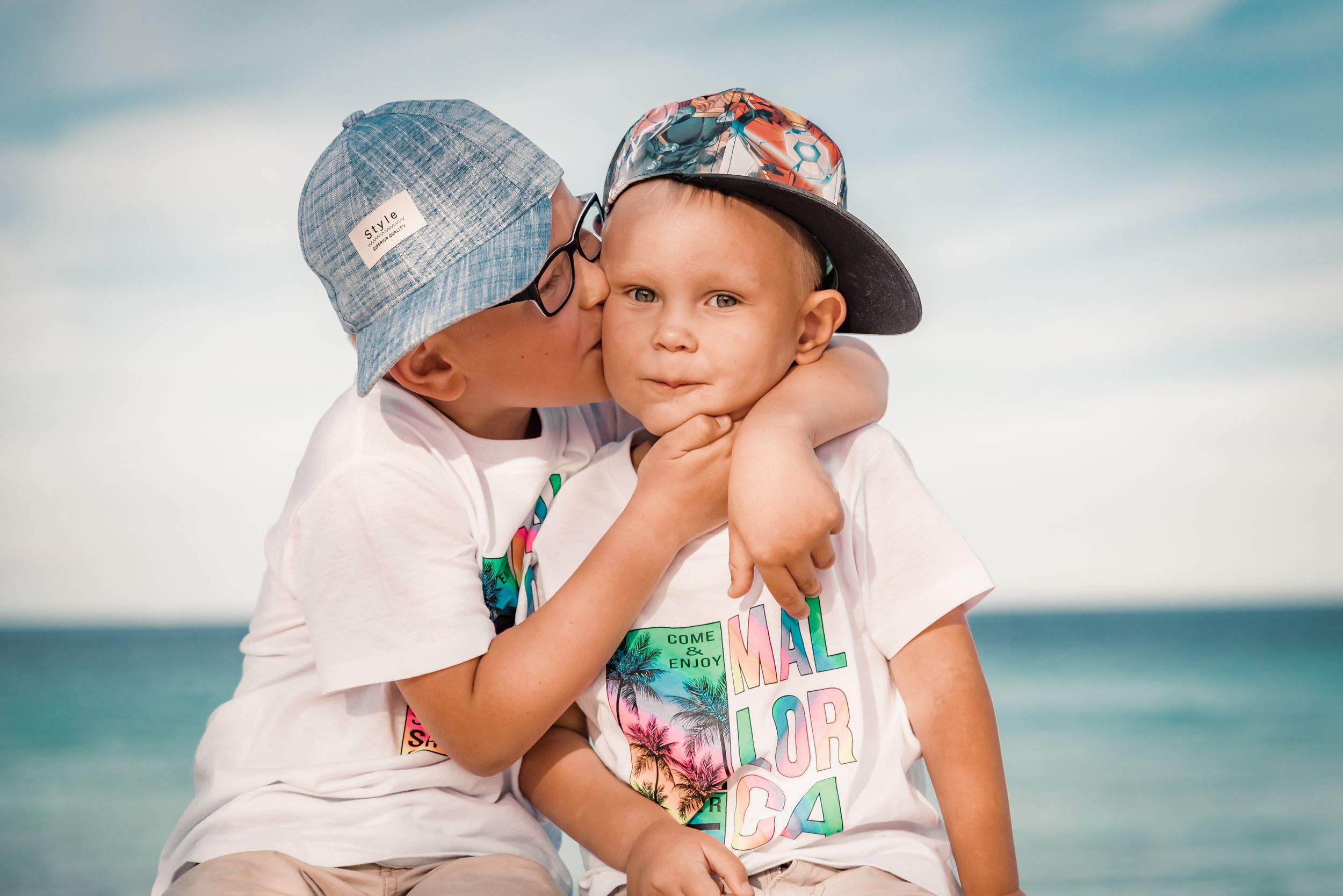Sweet, unscripted lifestyle portrait of two siblings hugging on the beach during a family vacation photo shoot in Mallorca.