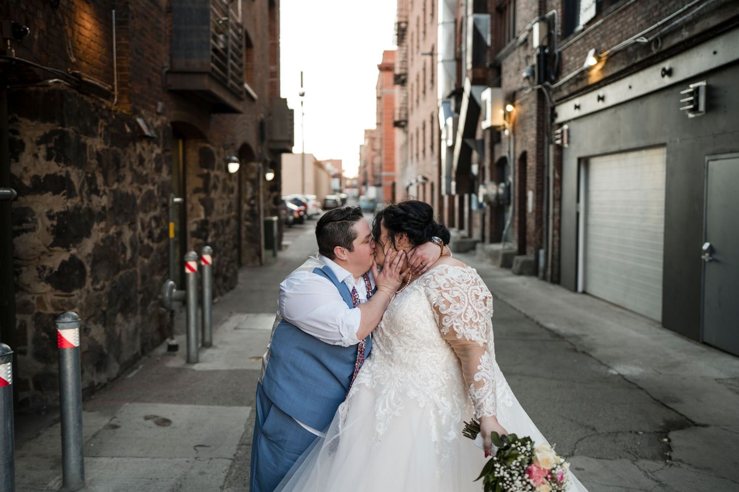 Couple sharing intimate moment in urban alley on wedding day.