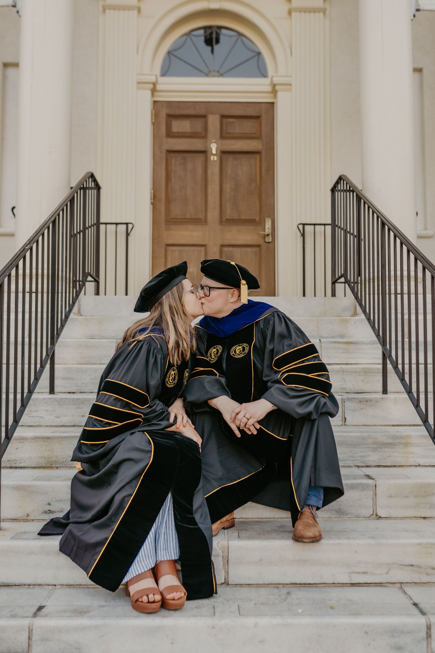 Two lesbian graduates kiss in the masters degree cap and gowns
