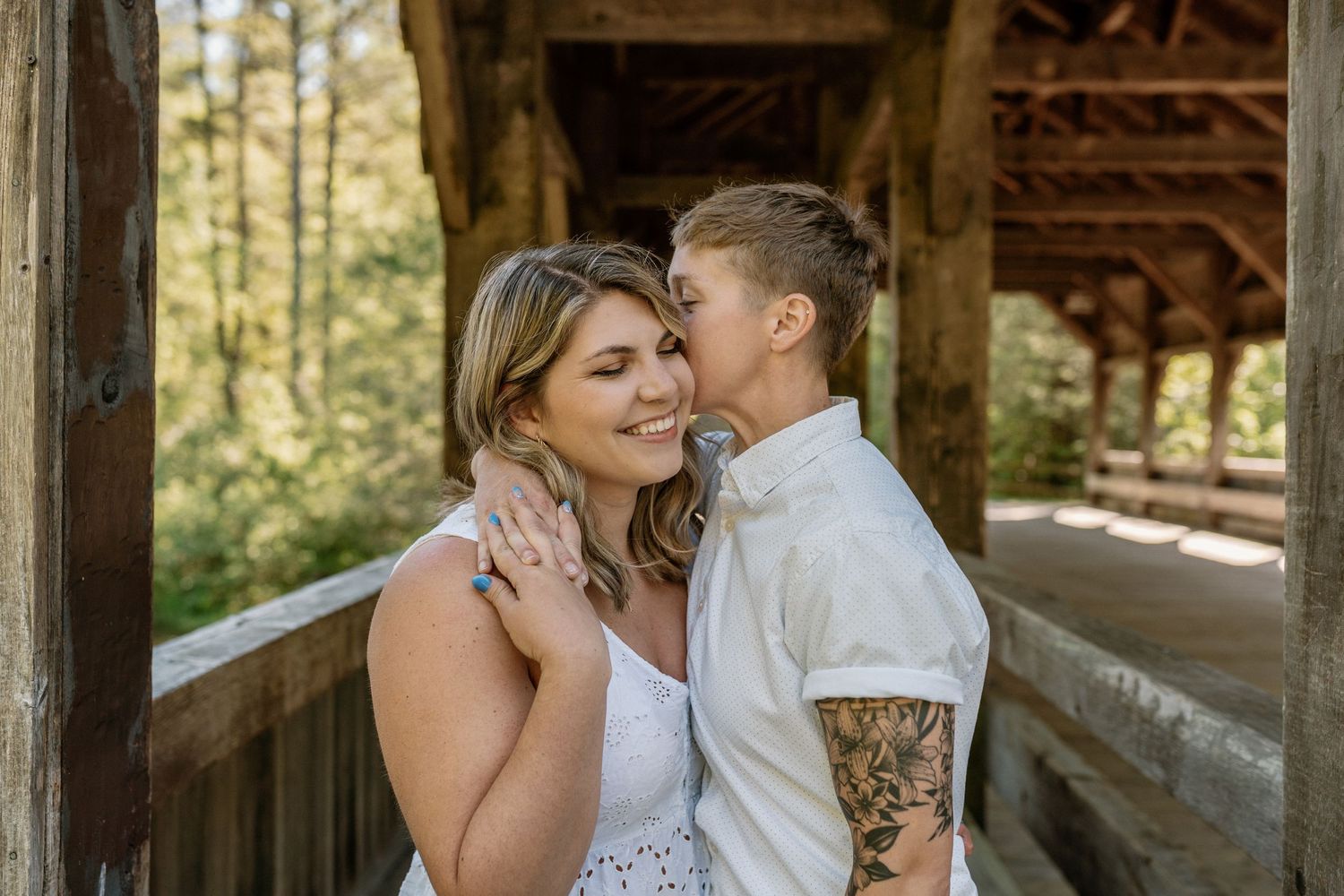 A gay couple kissing on a covered bridge