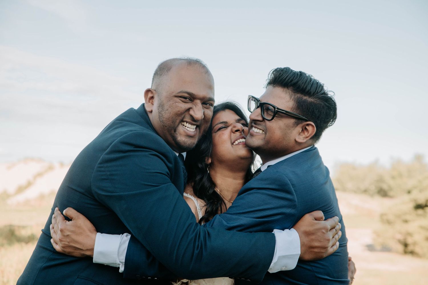 Joyful group hug captured outdoors against desert landscape.
