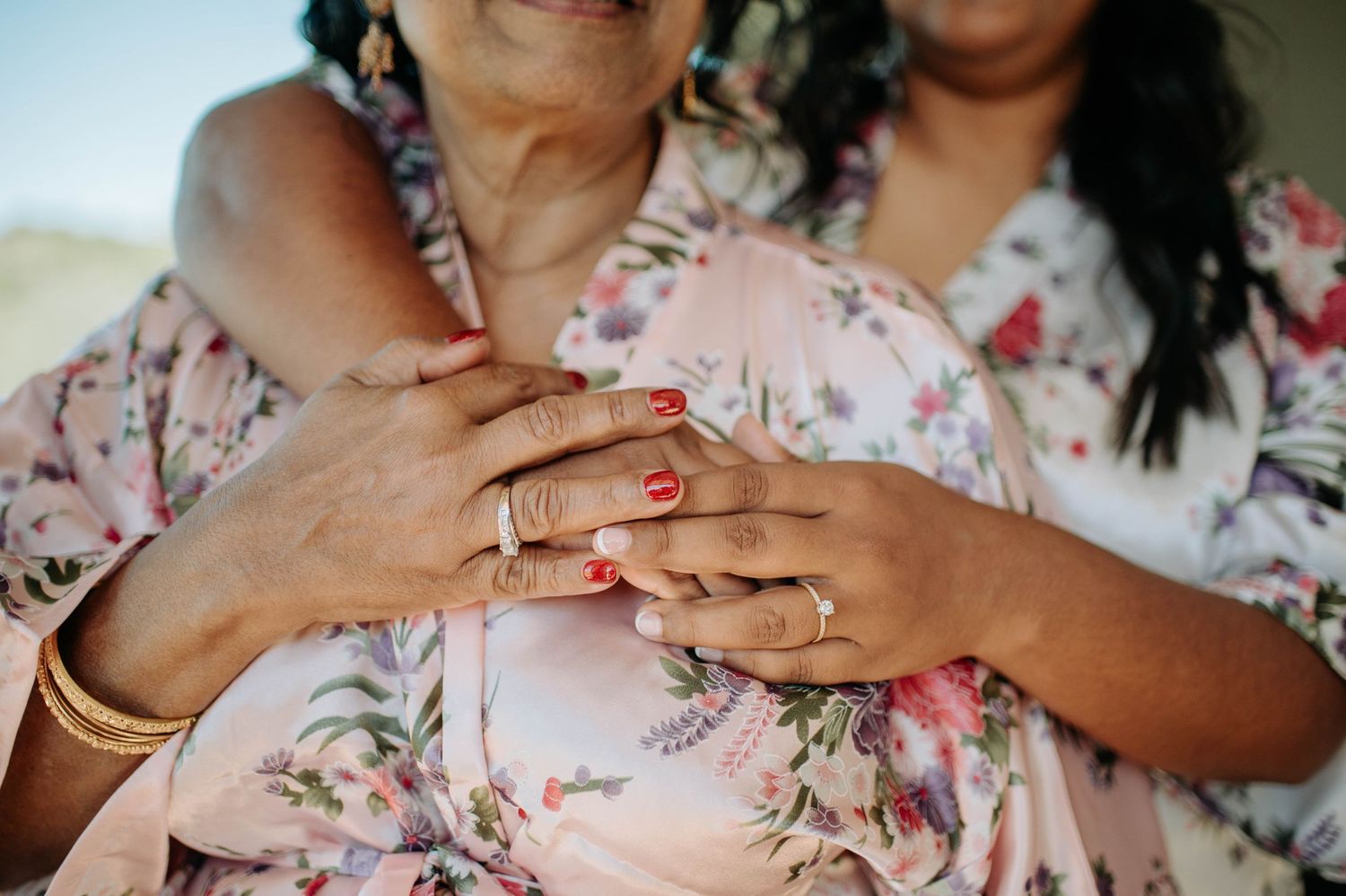 Close-up of hands with rings wearing floral robes showing wedding day preparations.