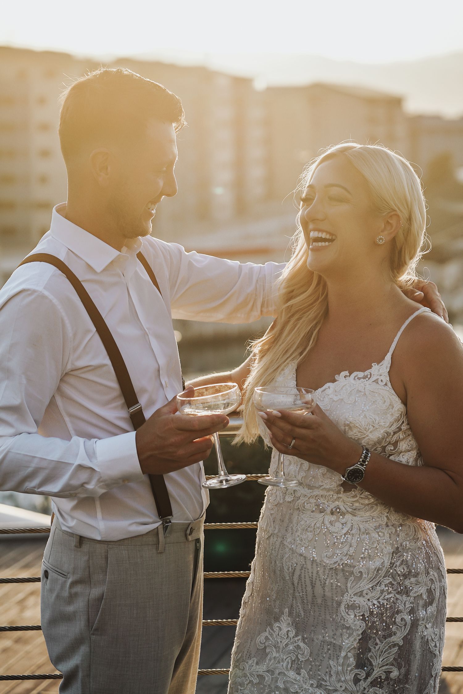Wedding couple on sunburn sunset laughing holding champagne