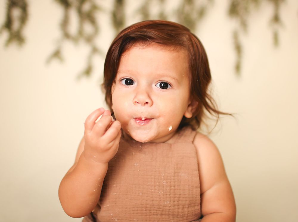 Baby boy in studio for cake smash session eating cake