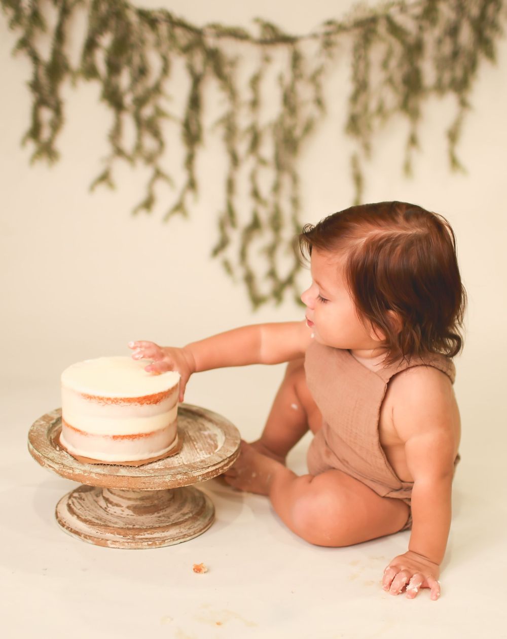 One year old digging into his first birthday cake