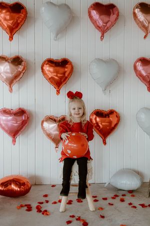 Cheerful Valentine's setup with rose gold and white heart balloons against white paneled wall.