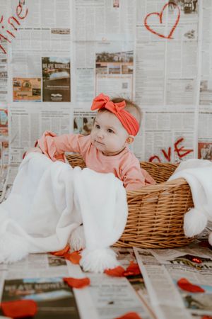 Vintage Valentine's setting with newspaper backdrop, wicker basket and coral accessories.