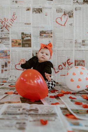 Valentine's photo setup with red heart balloons against newspaper backdrop.