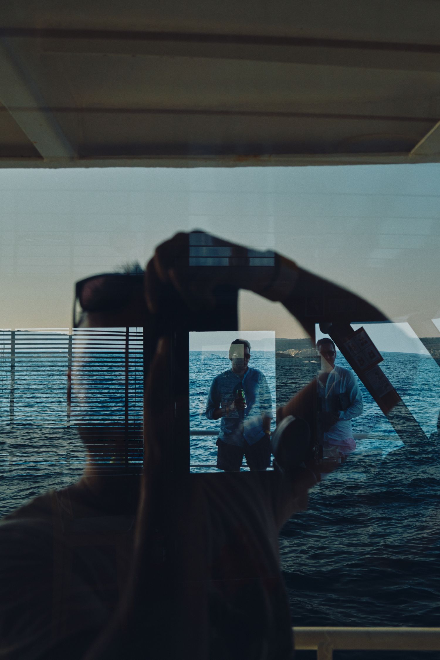 Through-window view of ocean horizon from inside a boat cabin.