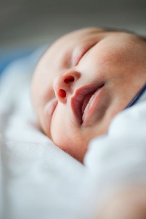 Close-up of sleeping baby's peaceful face against white bedding.