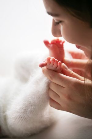 Tender moment of parent kissing baby's tiny foot held in gentle hands.