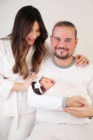 Happy family dressed in white sharing a tender moment with their newborn baby.