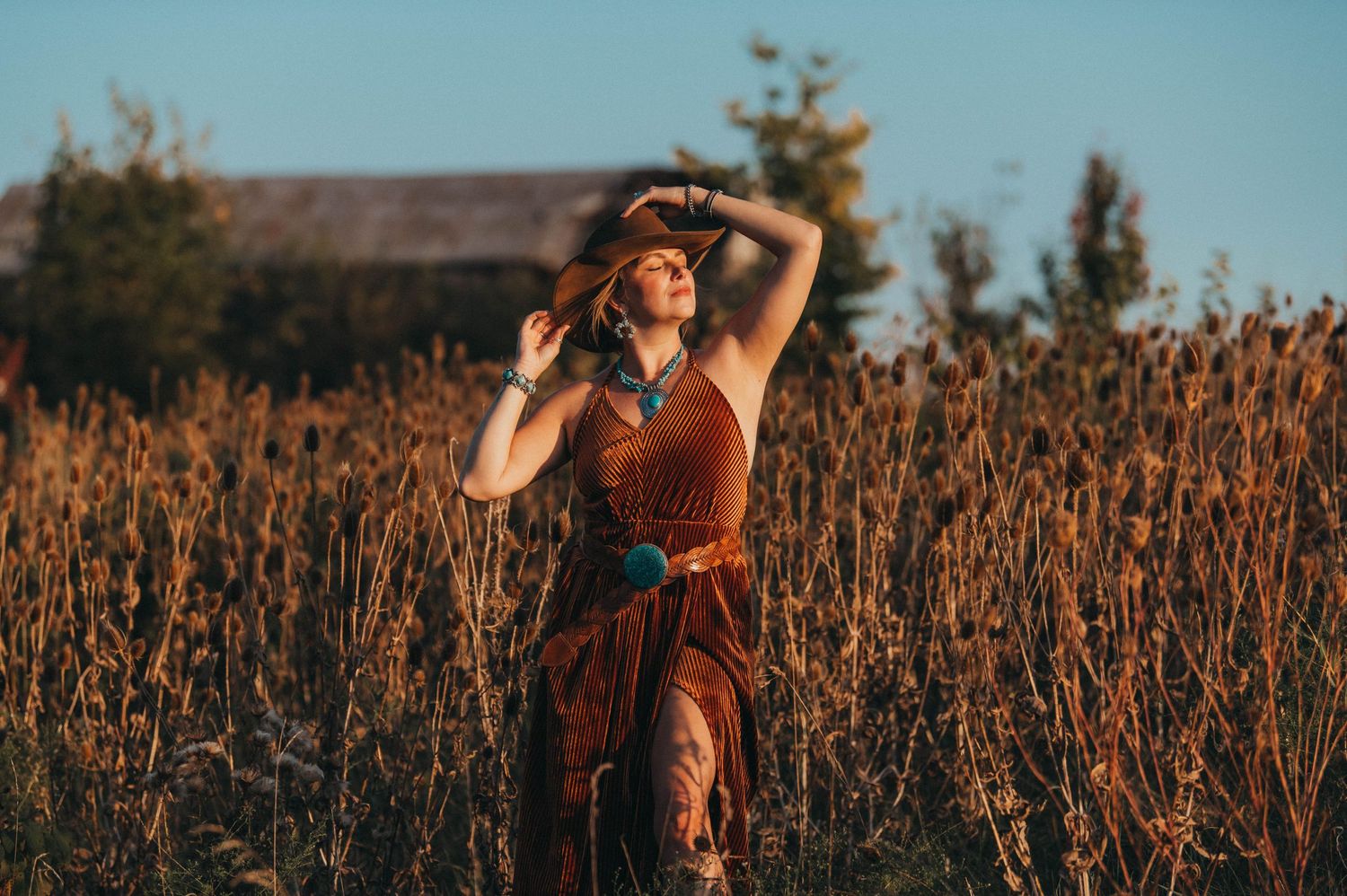 Woman in rustic dress dancing in wheat field during golden hour.