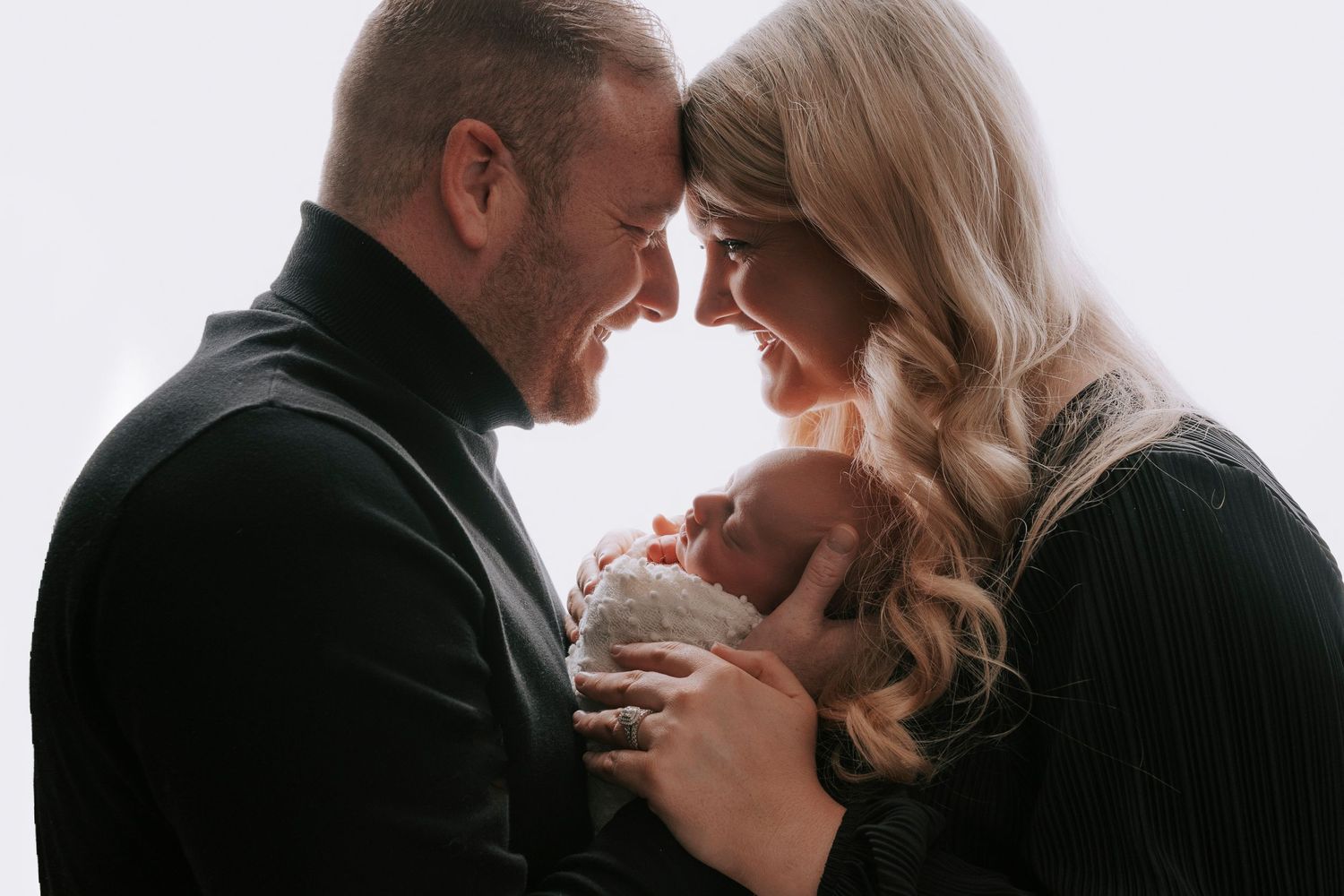 newborn baby girl in her fathers and mothers arms gazing lovingly into each other