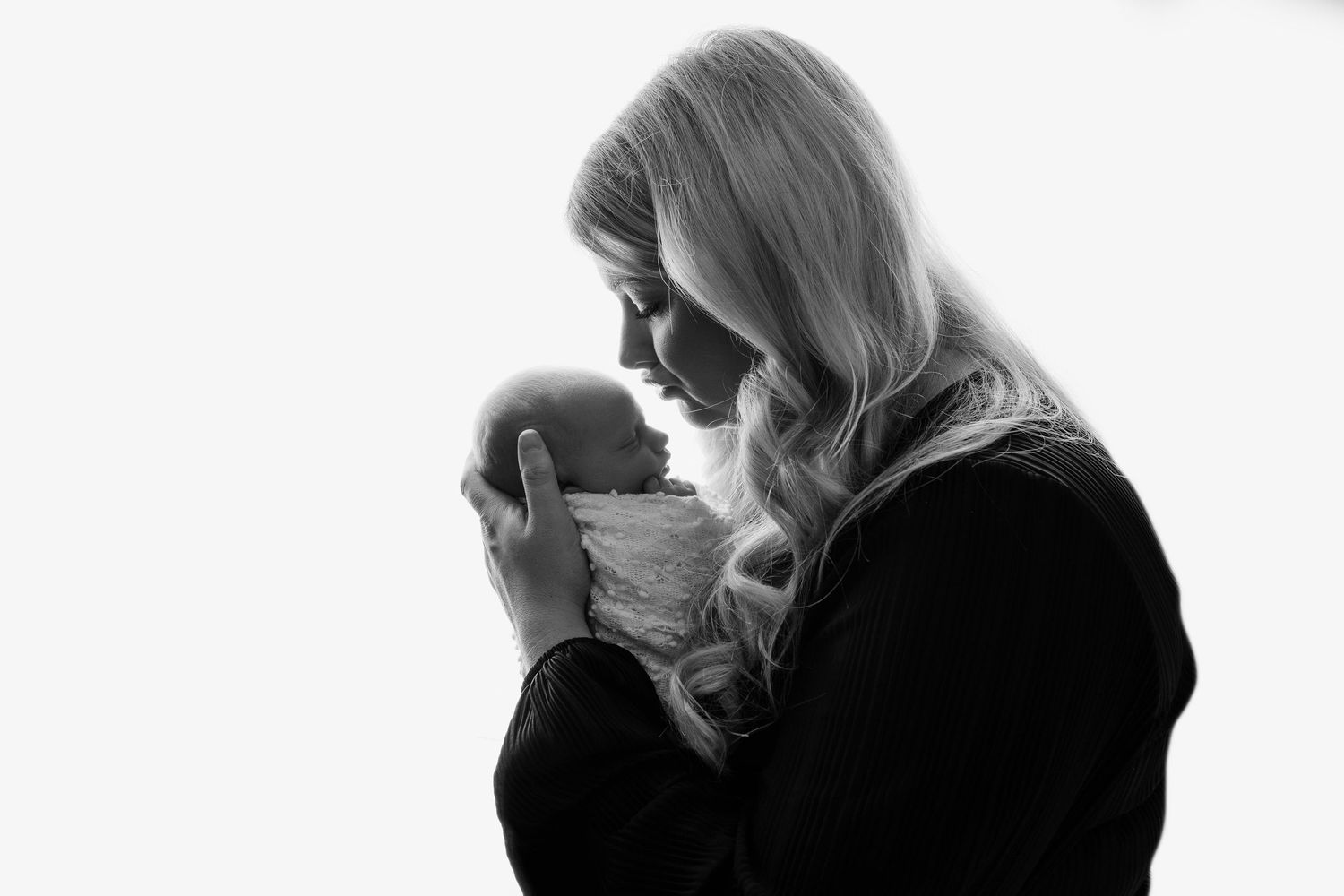 newborn baby girl in her mothers arms blowing a kiss
